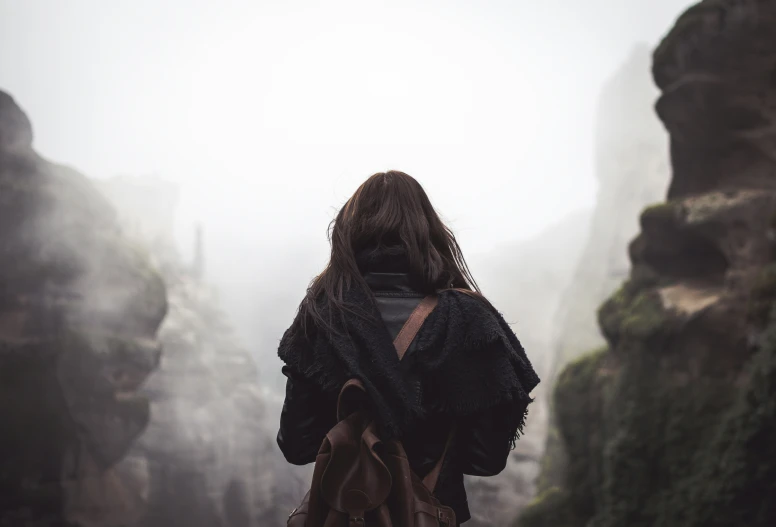 a woman wearing a coat and backpack is looking at a mountain