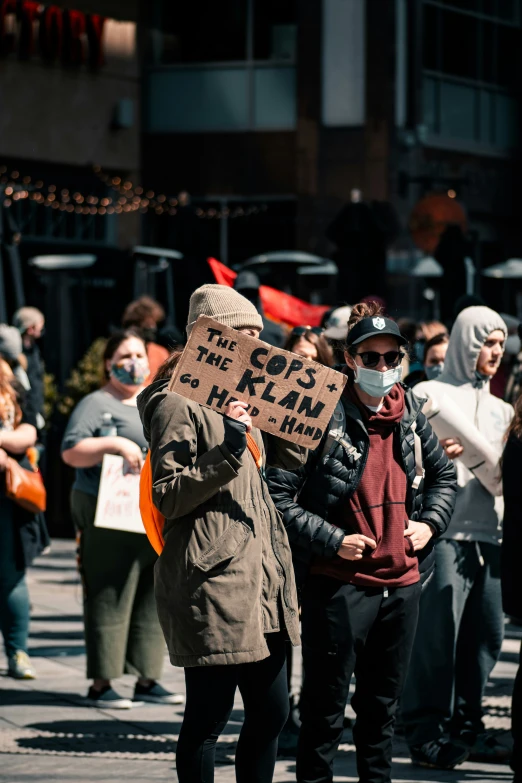 a couple of people standing in the street wearing a protest sign