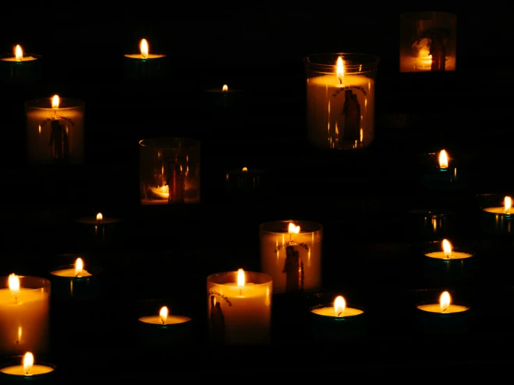 many candles are lit in a darkened room