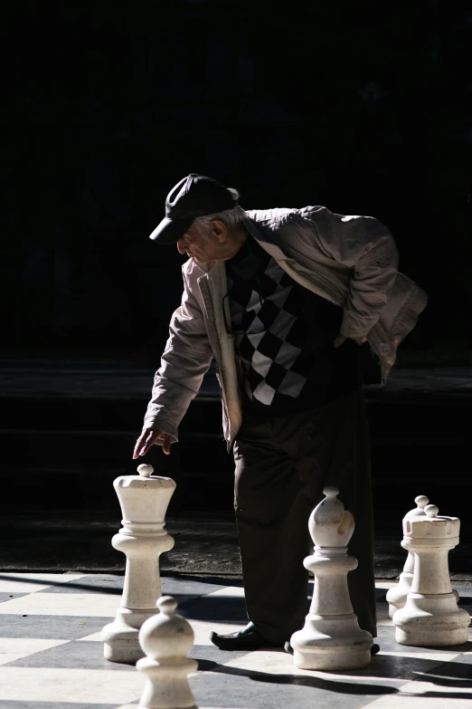 a person leans over two white chess boards