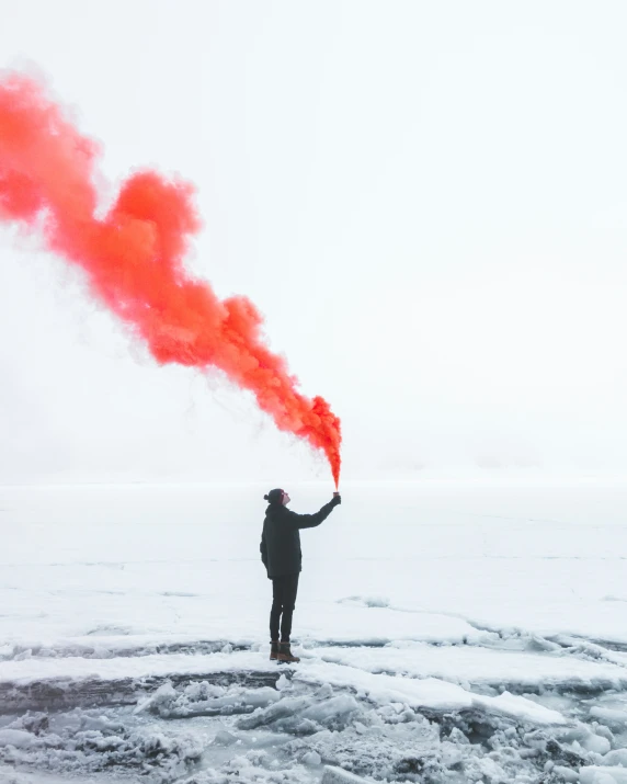 a person standing on top of snow covered ground holding an orange object