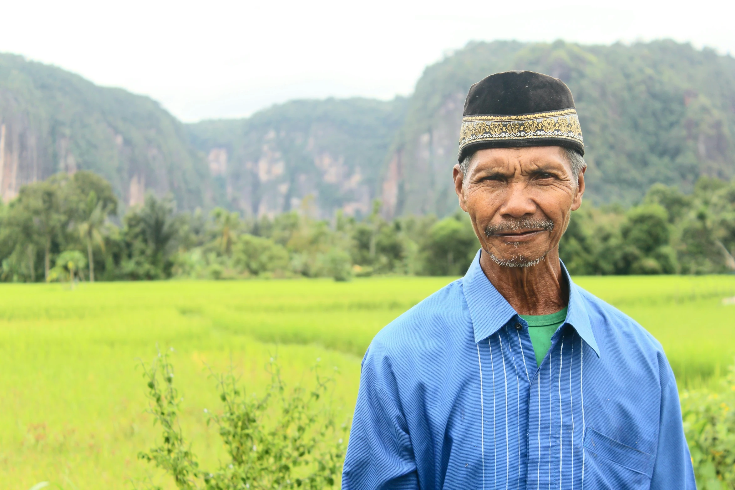 a man wearing an ethnic head piece with mountains in the background