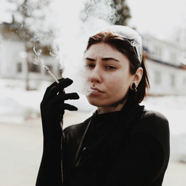 a woman wearing glasses smoking cigarette next to some snow