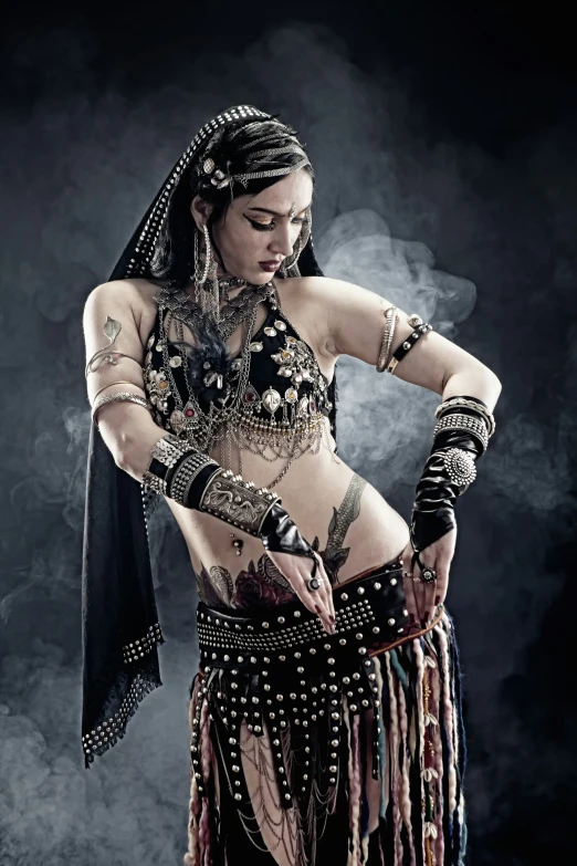 a woman wearing belly rings and skirt, standing in front of a dark background