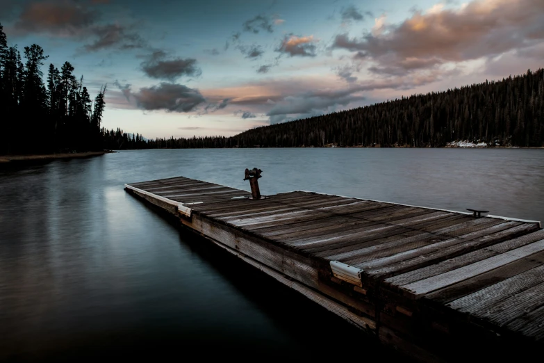 a person standing on a dock watching the sun set