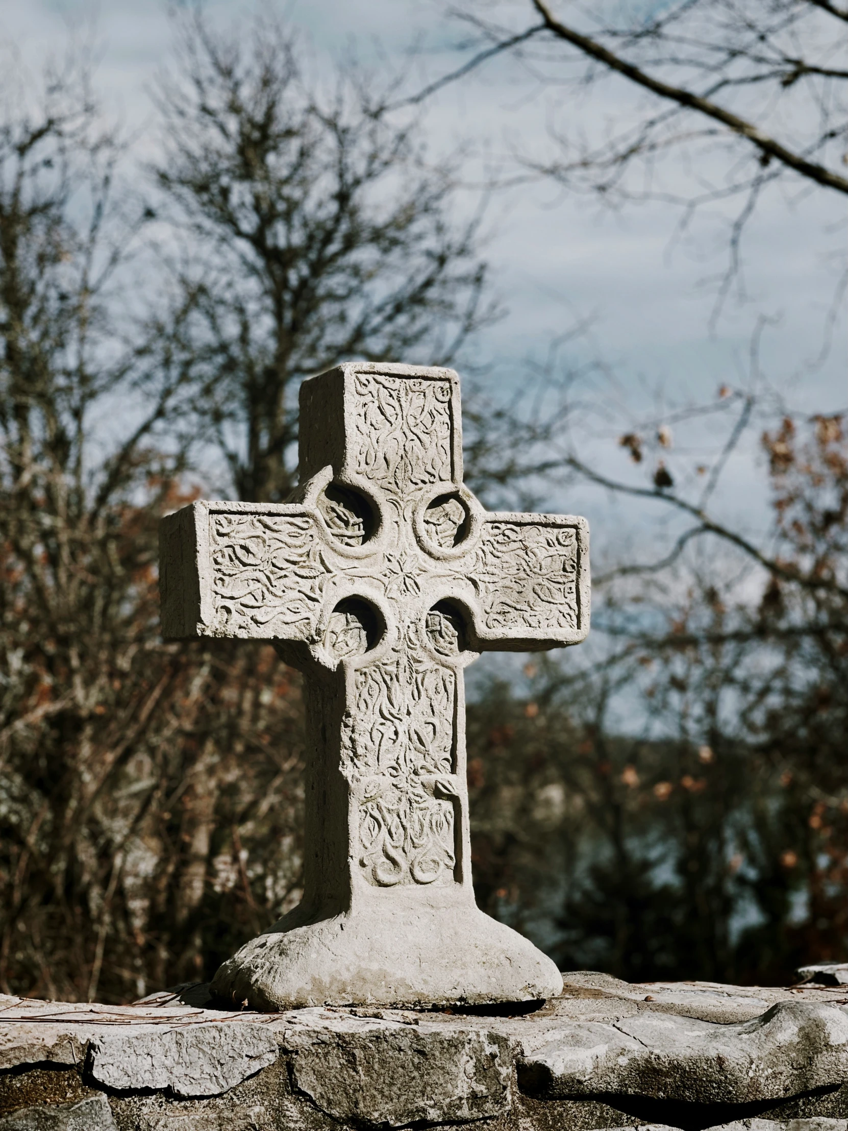 a white cross standing on the top of a stone wall