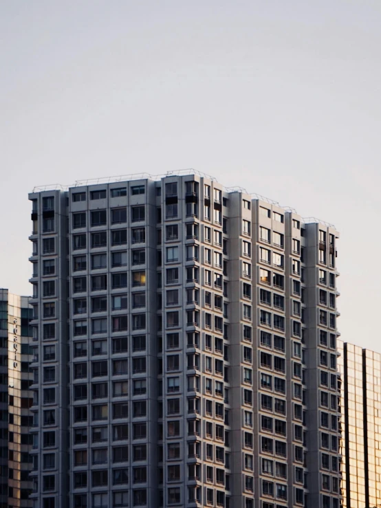 very tall gray building with lots of windows and an airplane flying in the distance