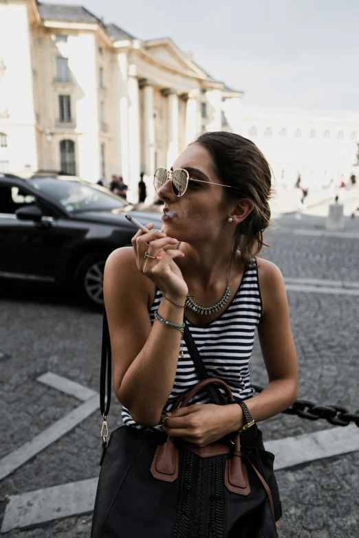 a woman wearing a necklace smoking a cigarette in the street