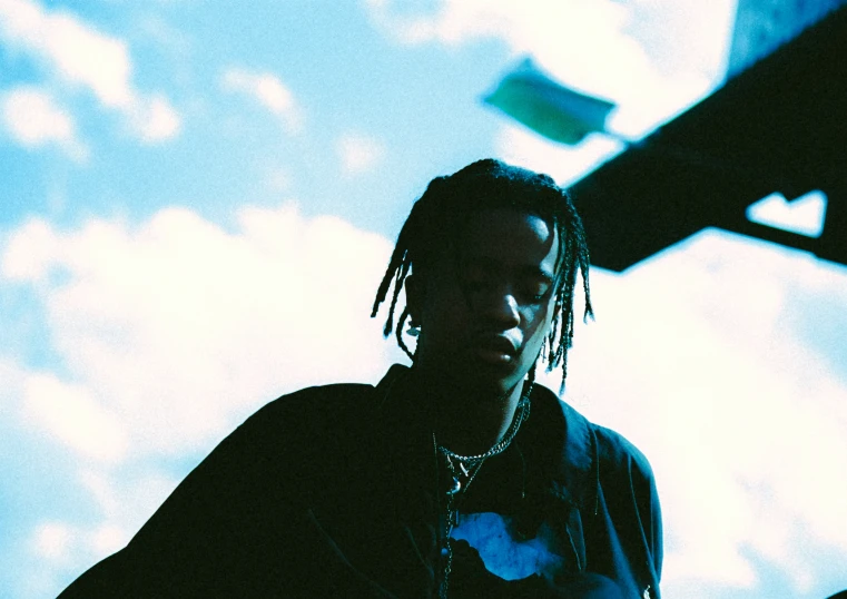 a man with dreadlocks standing against the sky