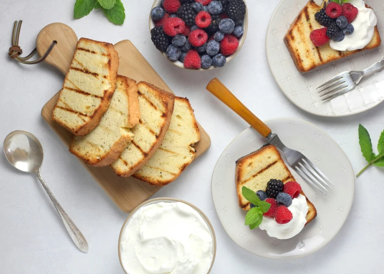 a table with slices of bread, berries and yogurt