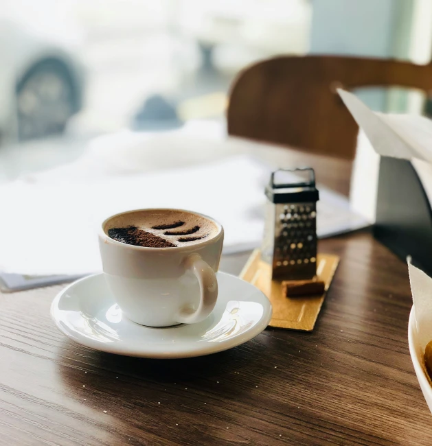 a table topped with a cup of coffee and a cell phone