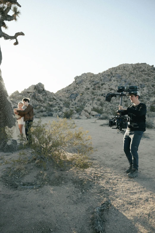 a couple of people holding a video camera in the desert