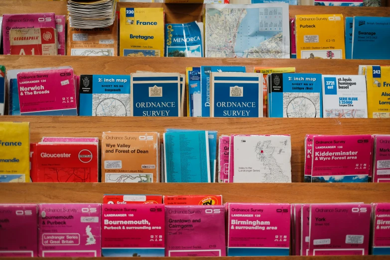 many different colored books sitting on a wooden shelf