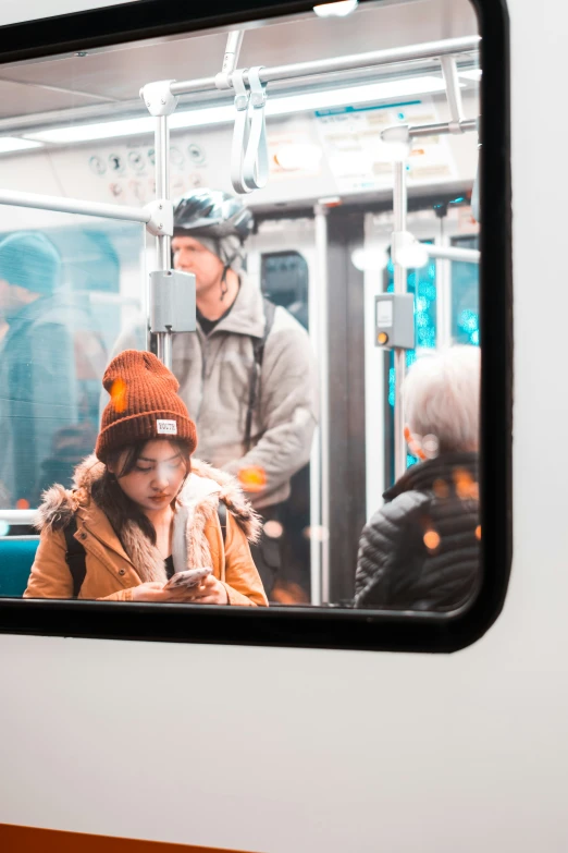 the girl in a winter hat is looking down at her cell phone