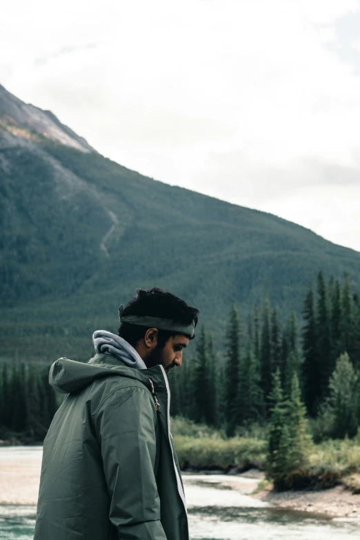 a man wearing a jacket standing next to a body of water