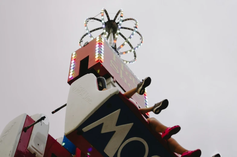 a woman laying on top of a pole with an upside down ferris wheel