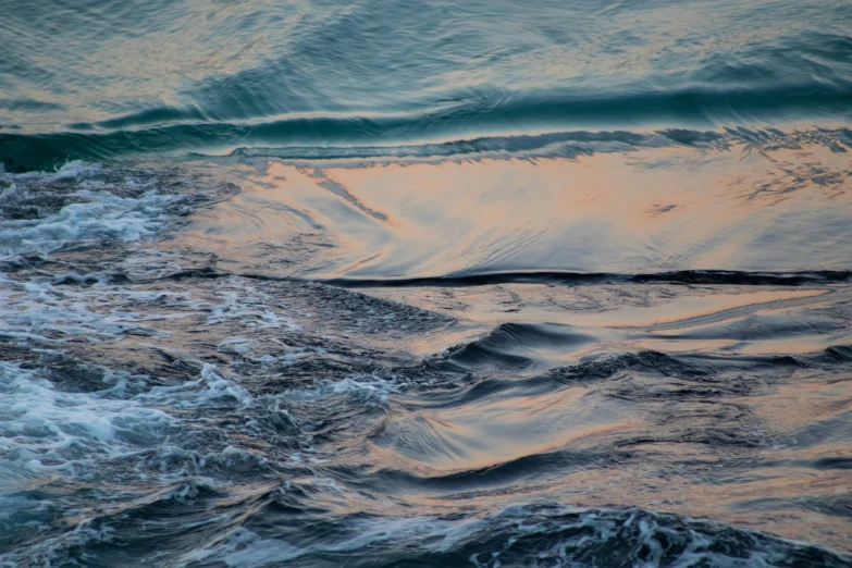 water waves splash against the rocks as the sun goes down