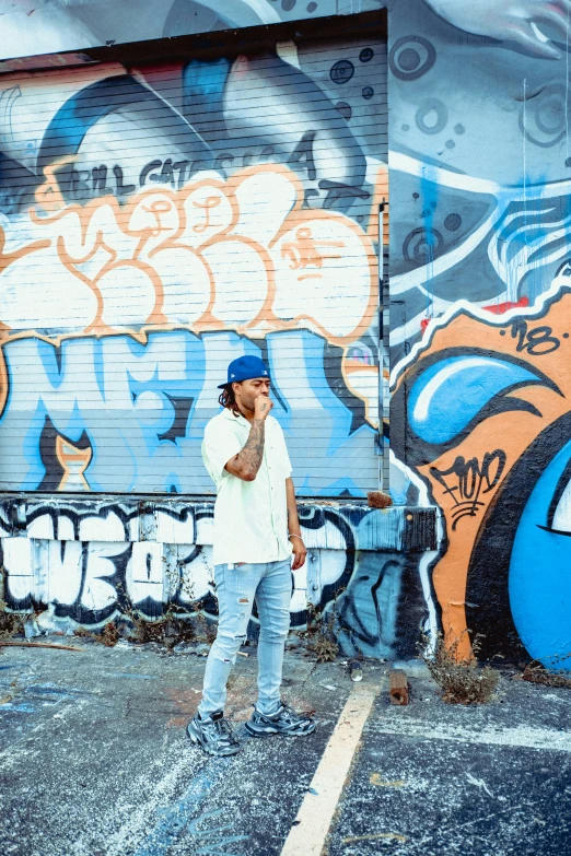 a man standing next to a colorful wall with graffiti