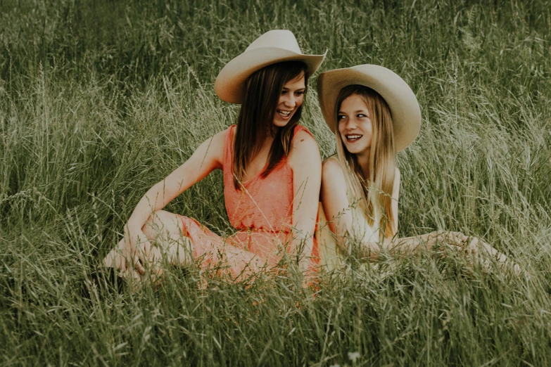 two women sit in a field smiling