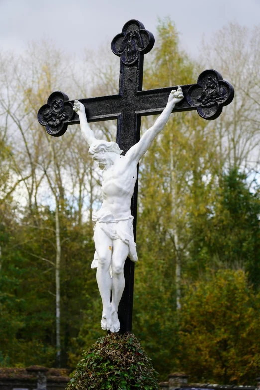 a statue of jesus hanging on a cross in a park