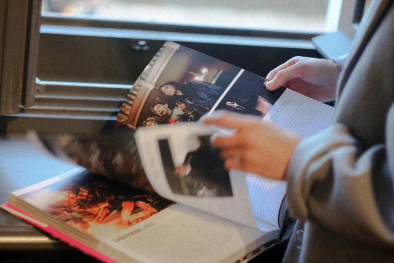 a man standing next to a window holding an open magazine