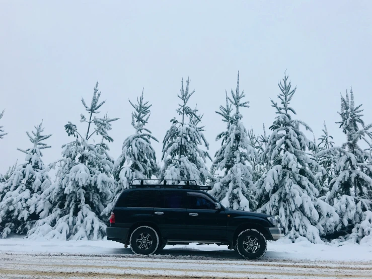 an suv parked in the middle of a snow covered road