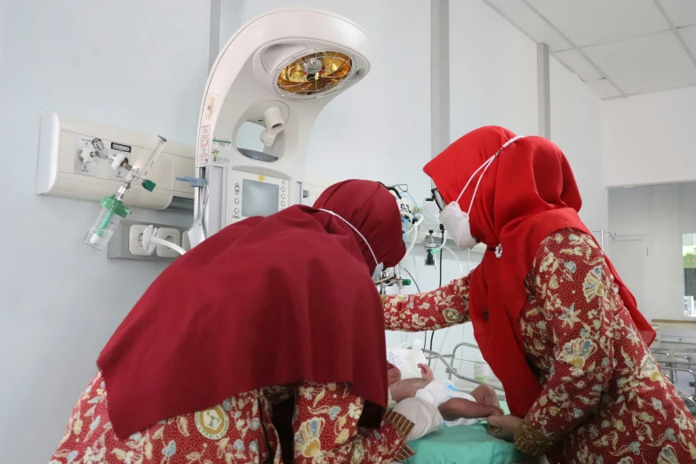 two women in red are preparing a patient