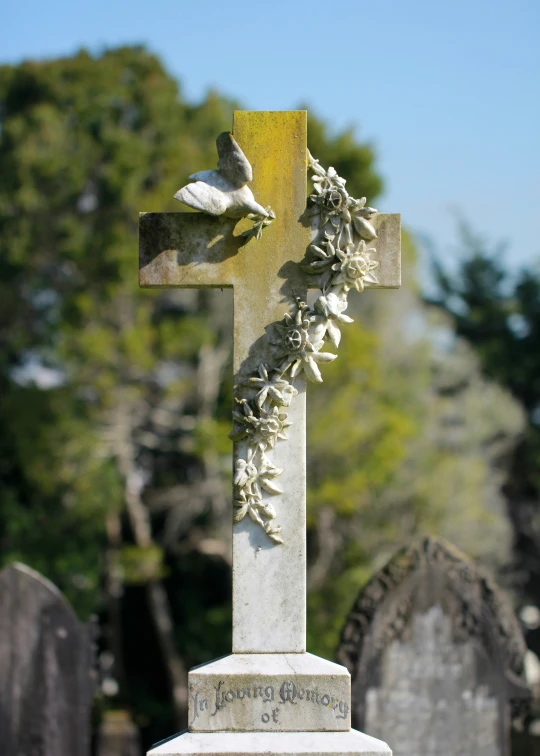 a cross with flowers on it and leaves hanging down