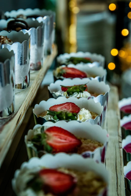 strawberries are on display on metal trays in a row