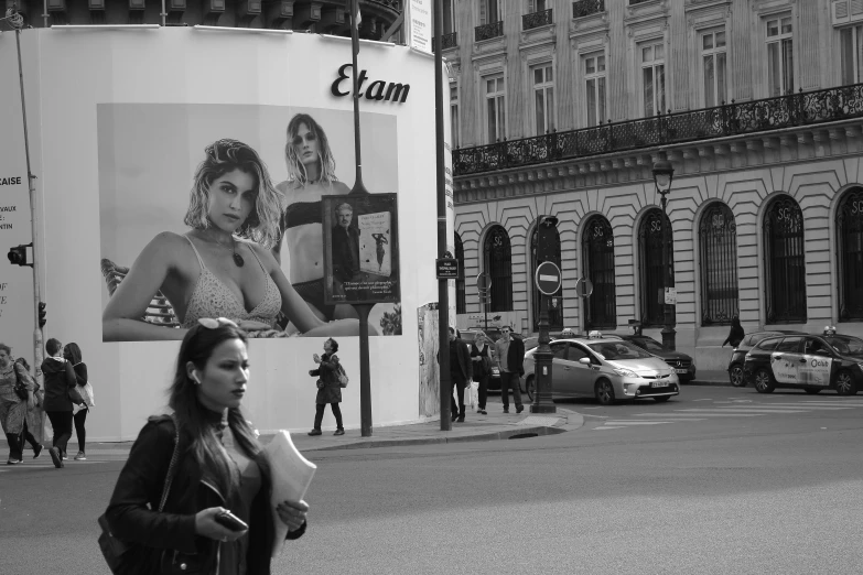 a lady walking down the street past an advertit with a girl in it