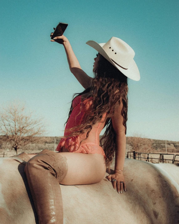 a woman in a cowboy hat on top of a white horse