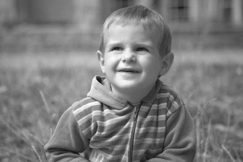 a young child smiles while sitting in the grass