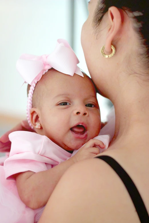 a  in a pink dress being held by a mother