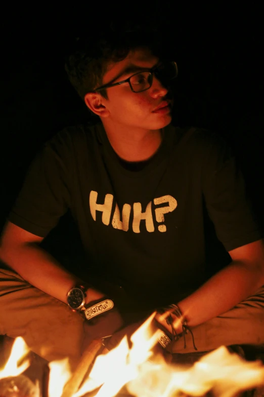 a boy sitting in the middle of a campfire