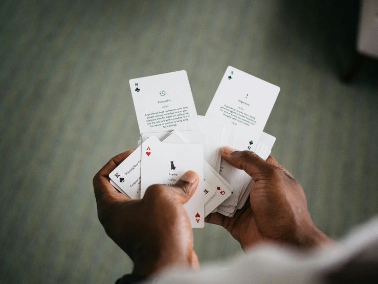 a man holding three playing cards over some other ones