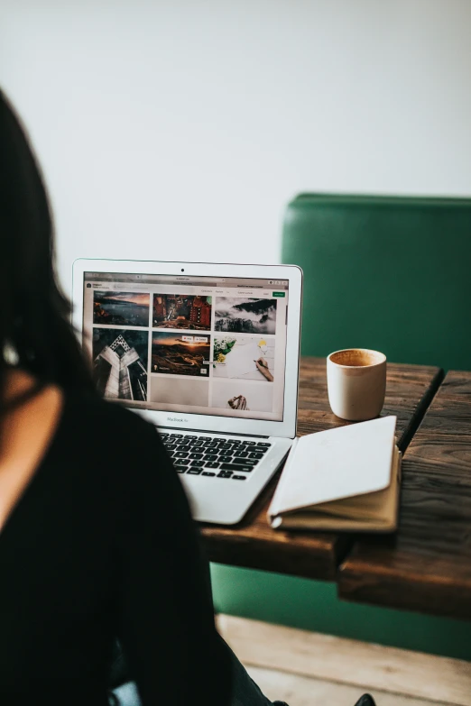 a woman sitting at a table looking at her laptop