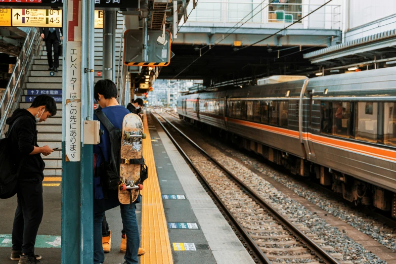 several people waiting in a train station near a train