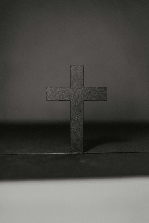 the cross is sitting on the table next to the window