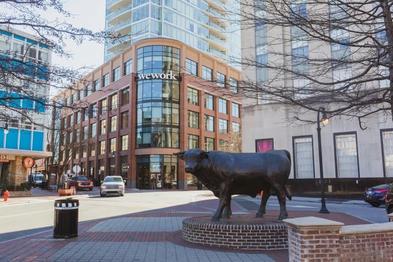 a bronze cow statue sitting in front of a tall building