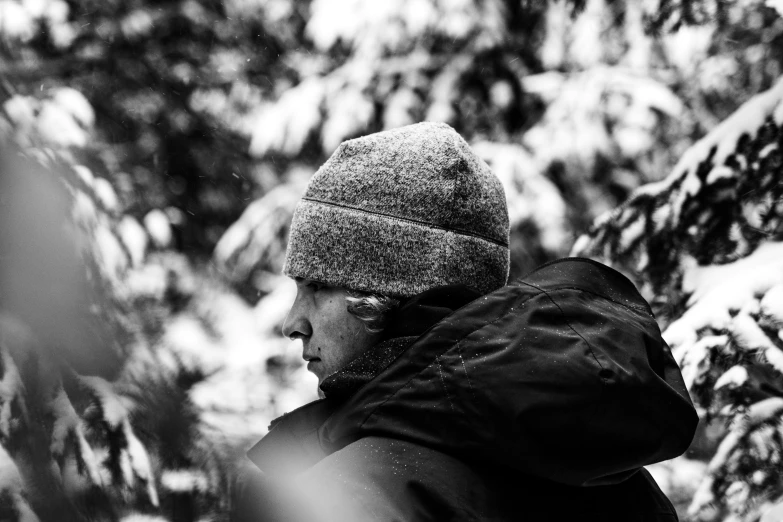 a person in a hooded hat stands next to a tree