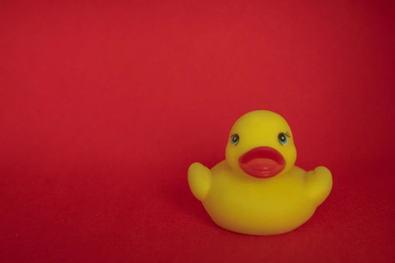 there is a yellow rubber duck sitting on a red background