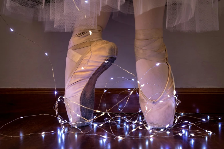 the feet of a ballerina wearing white dress shoes