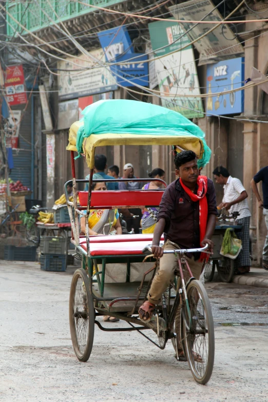 man riding bicycle cart with green cloth covering