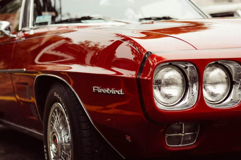 an old red chevy camaro sits in front of a street