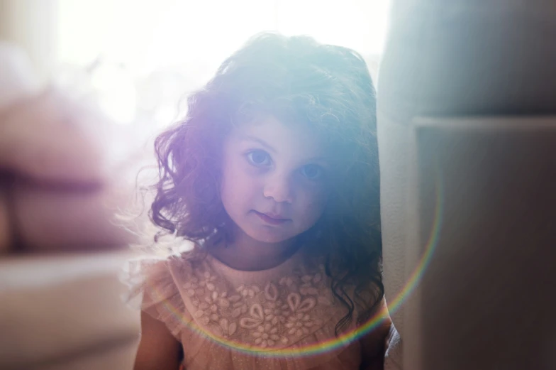 a little girl standing next to a white couch