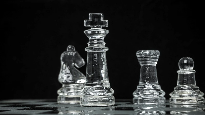 the glass chess pieces are arranged on a checkered surface