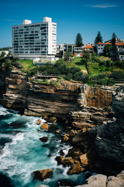 a high rise building next to an ocean cliff near a city