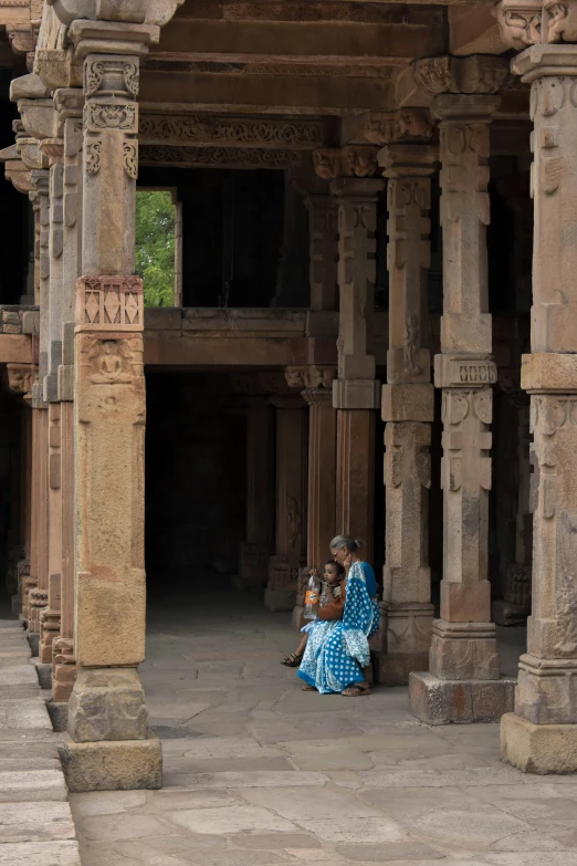 a woman sits under some pillars in a large building