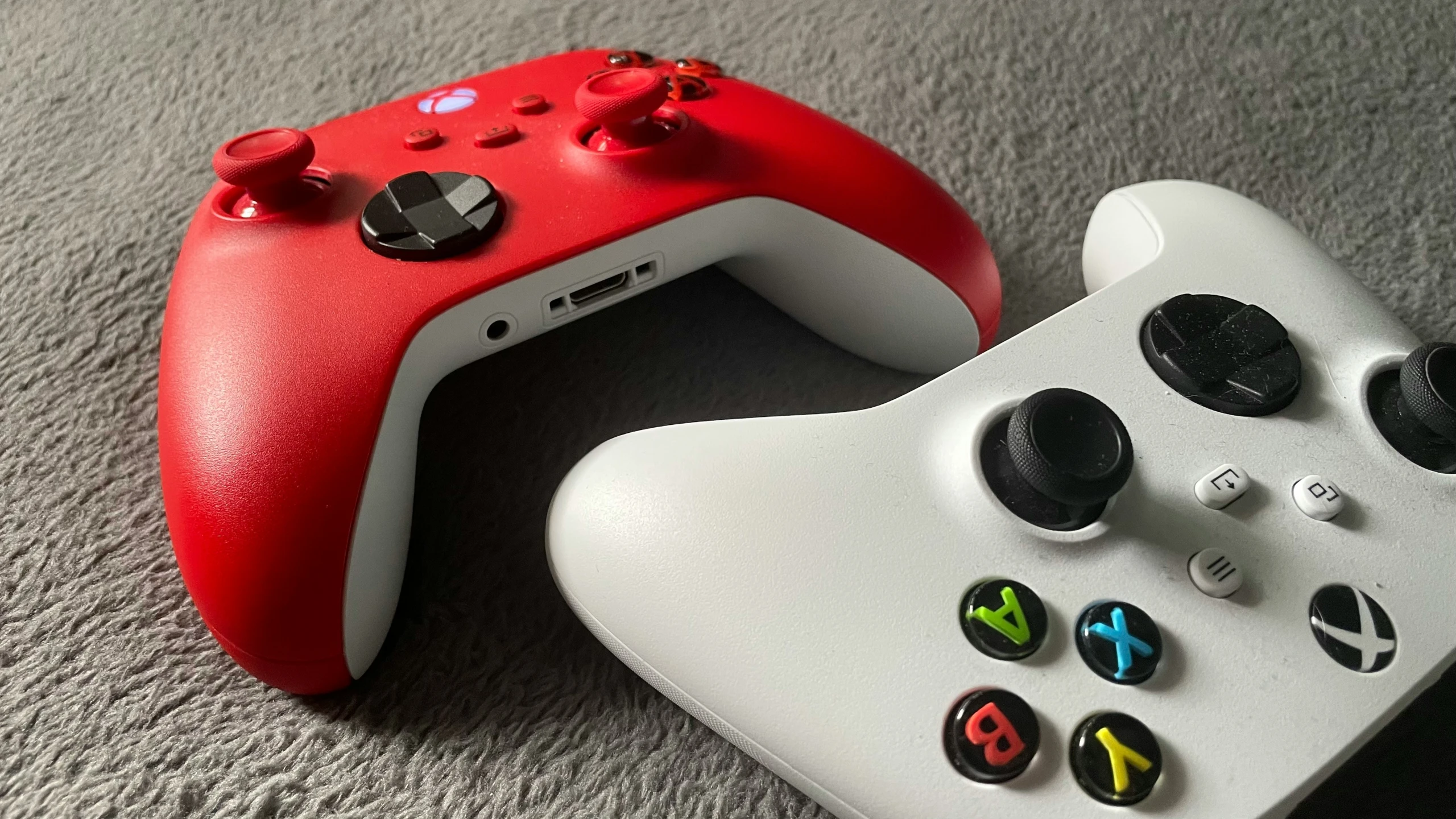 two video game controllers sit on the carpet