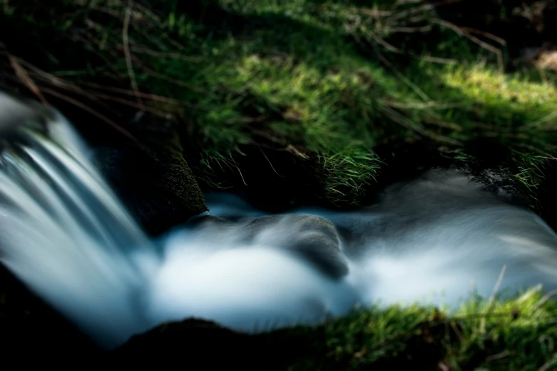 a stream with rocks in the grass next to it